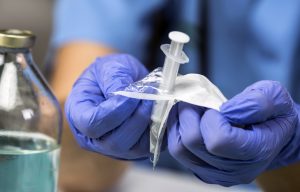 Nurse opens a new syringe in a hospital, conceptual image