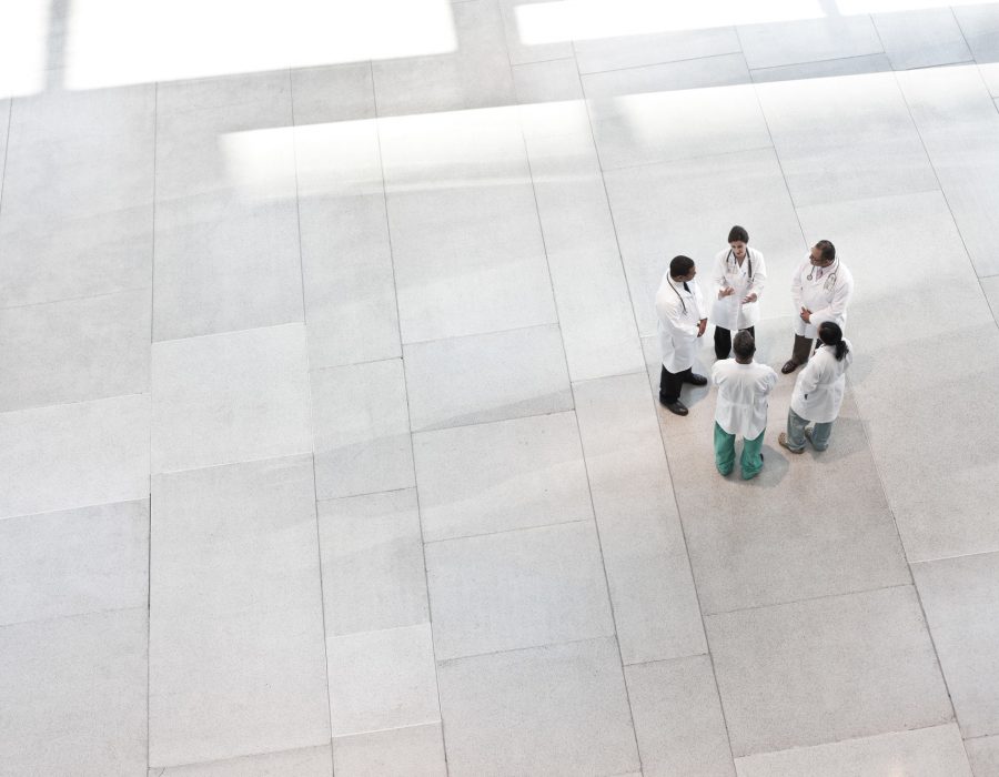 Mixed race group of doctors meeting in lobby of large hospital