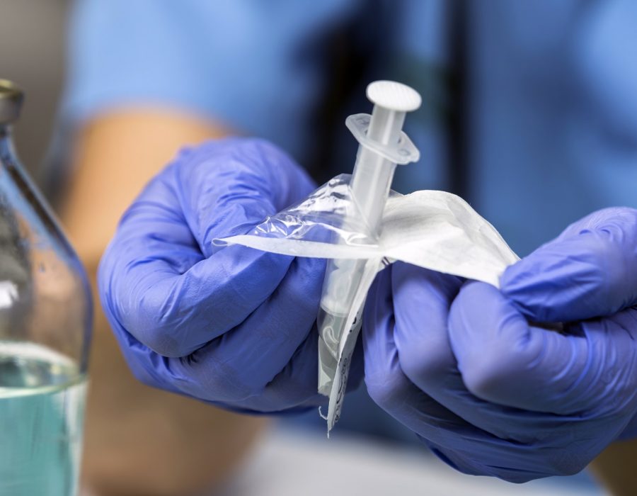 Nurse opens a new syringe in a hospital, conceptual image